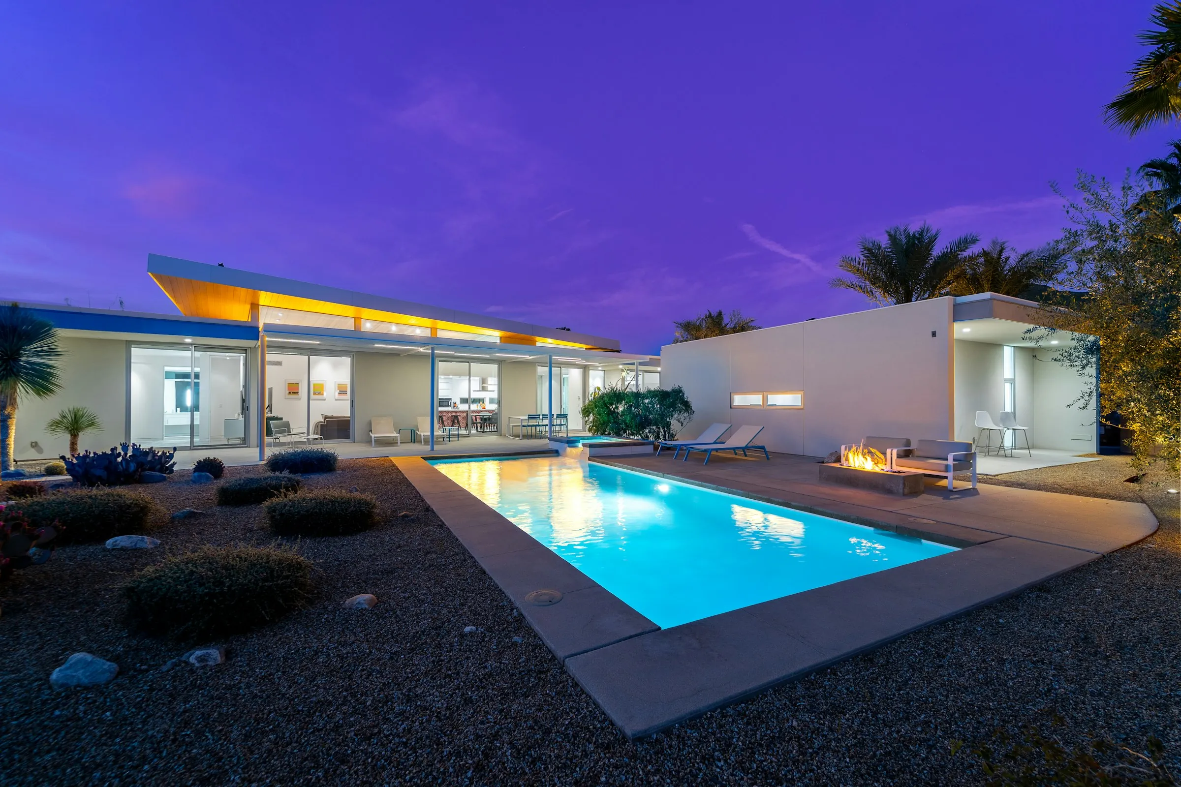 Modern home with a lit pool at night